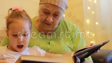 <strong>外婆</strong>和孙女一起看书.. 祖母拥抱和亲吻她的孙女。